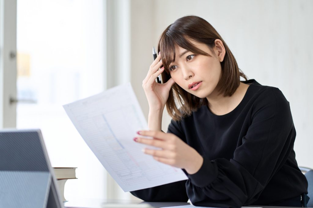 書類を眺めて困っている女性のイメージ画像